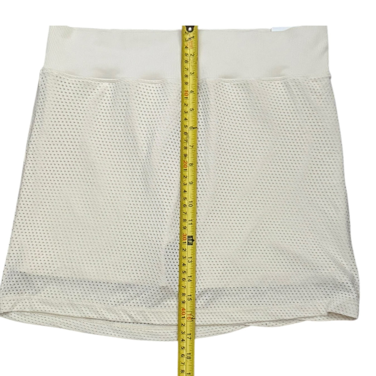 Mesh skort shown flat on a white background with a yellow measuring tape running vertically down the center to indicate size.