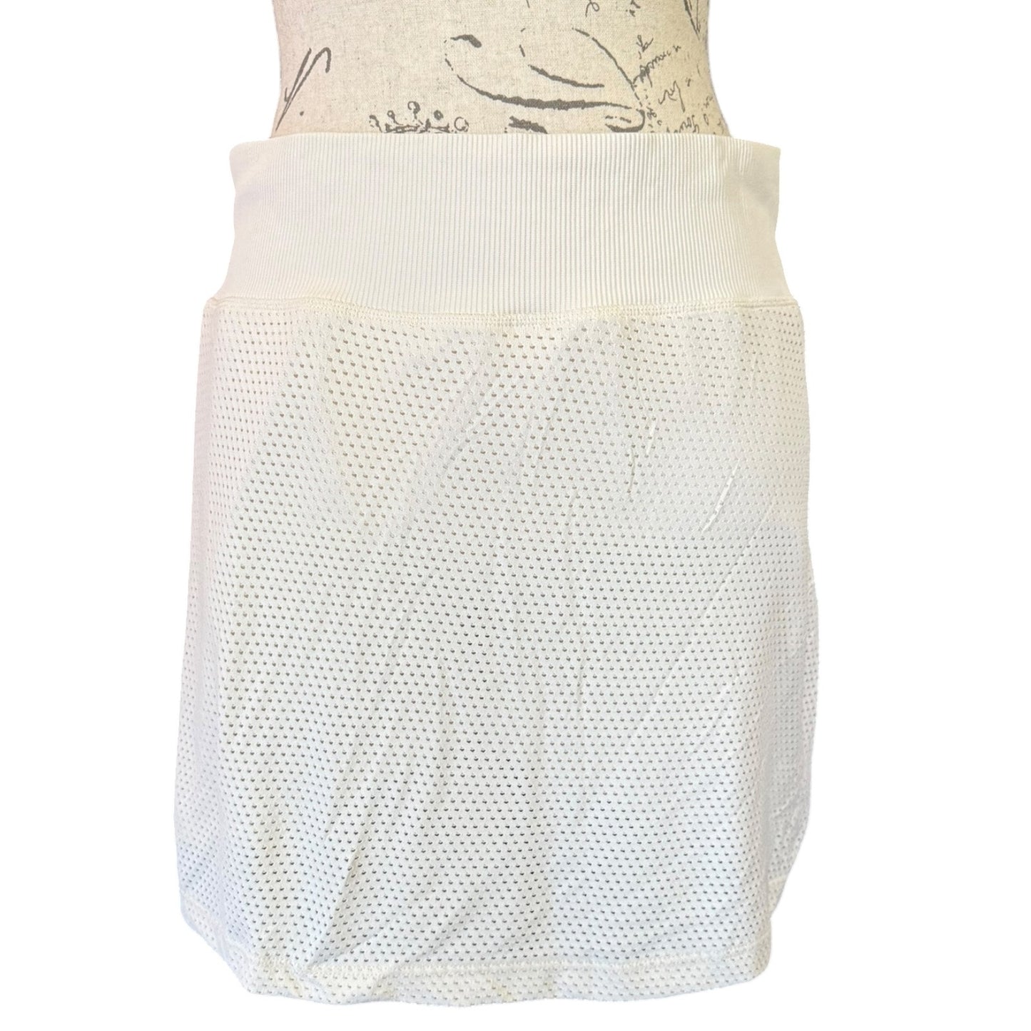 An mesh skort with a wide ribbed waistband, displayed on a mannequin torso against a plain white background.