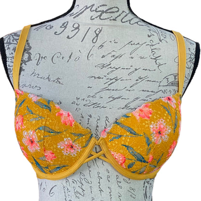 A Victoria's Secret Pink floral push-up bra displayed on a mannequin with yellow straps and a pink flower pattern on the cups.