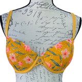 A Victoria's Secret Pink floral push-up bra displayed on a mannequin with yellow straps and a pink flower pattern on the cups.