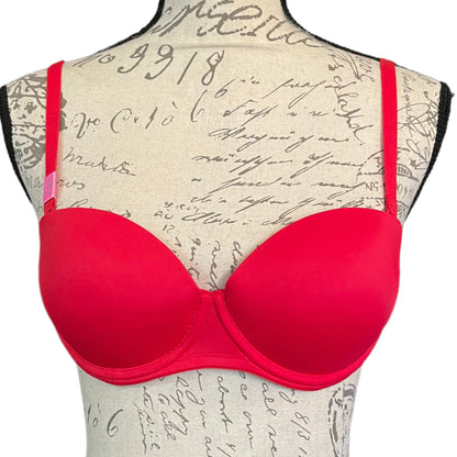 A red Victoria's Secret Pink bra displayed on a mannequin with a textured backdrop.