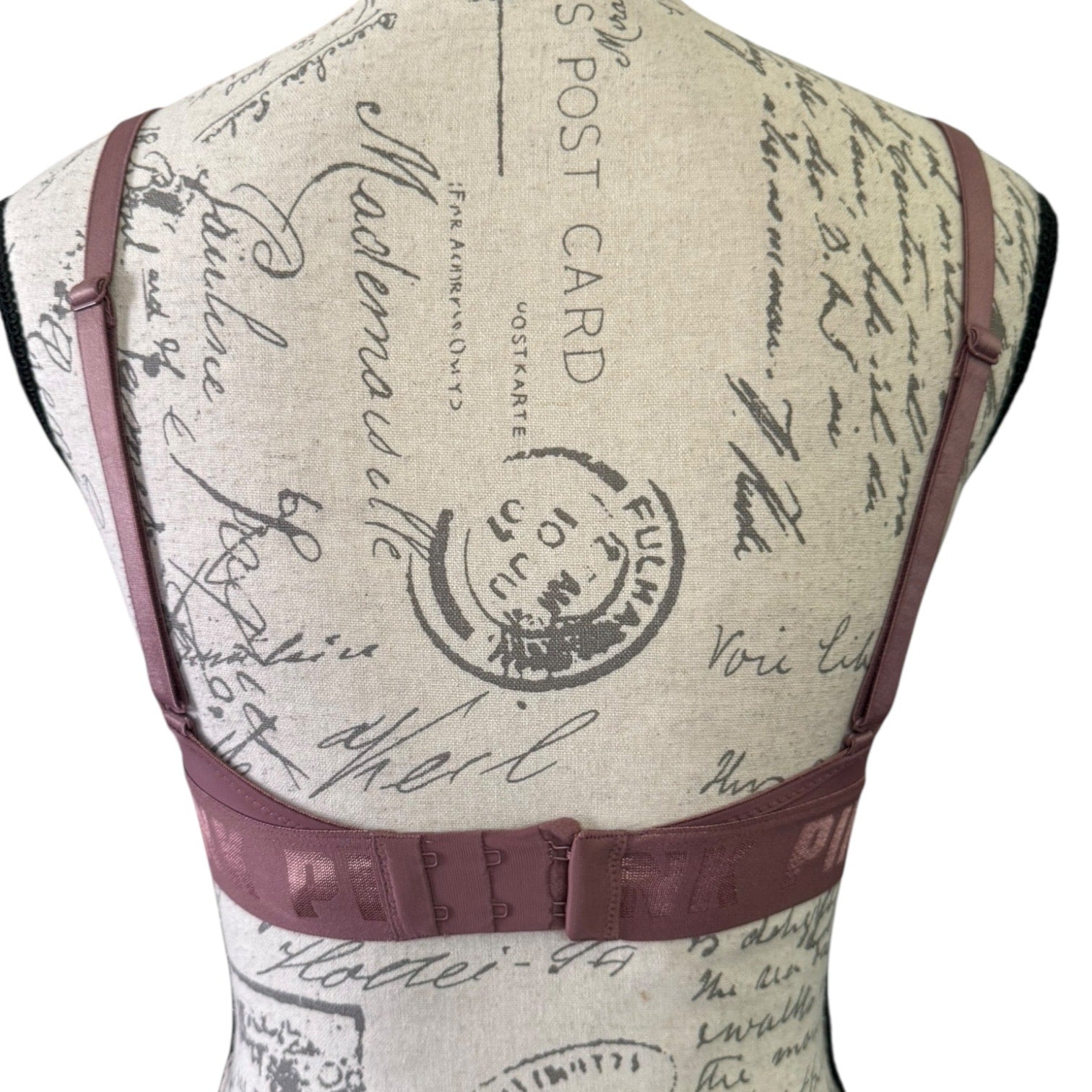 Back of purple bra with vintage-style text and stamp design on a beige background