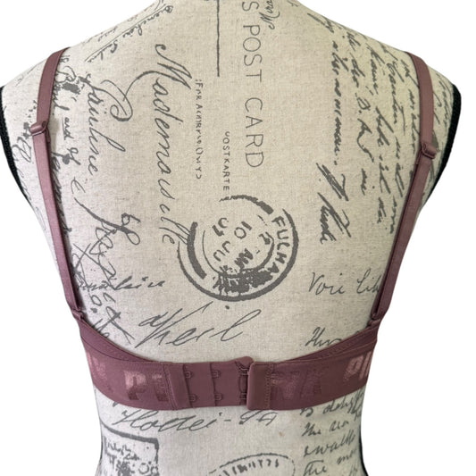 Back of purple bra with vintage-style text and stamp design on a beige background