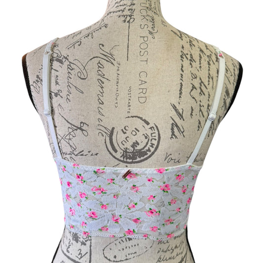 Back of bralette top displayed on a fabric dress form. The garment features a white lace bodice with pink floral print and a solid white upper yoke, with thin white shoulder straps.