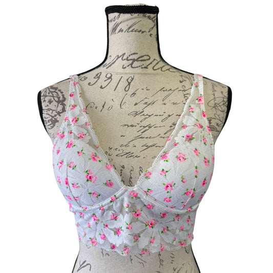 White lace underwire bra with pink floral print, displayed on a vintage-style fabric mannequin torso against a white background.