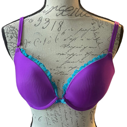 Front of Purple bra with teal lace trim on a mannequin with script background