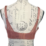 Back of pink bra on a mannequin with a vintage-style postcard background