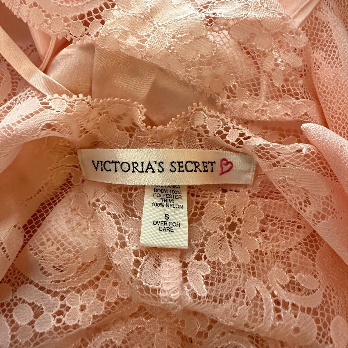 Close-up of a Victoria's Secret garment showing the brand label sewn onto  lace and satin fabric.