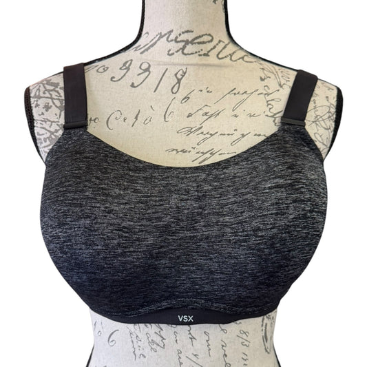 A dark heather black sports bra displayed on a vintage-style mannequin torso with cursive script writing on a white background.