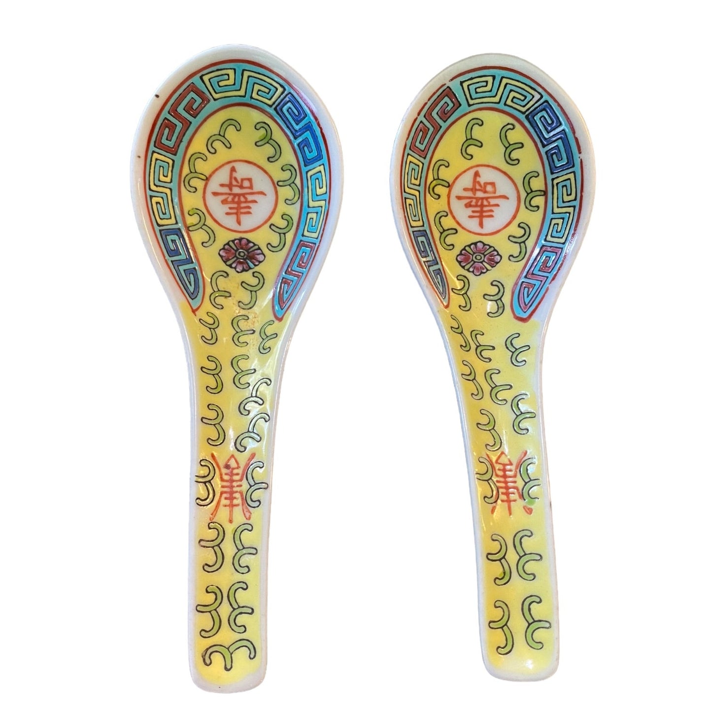 Two decorative Chinese spoons with a yellow and white glaze, featuring traditional Chinese patterns in blue, green, red, and gold.
