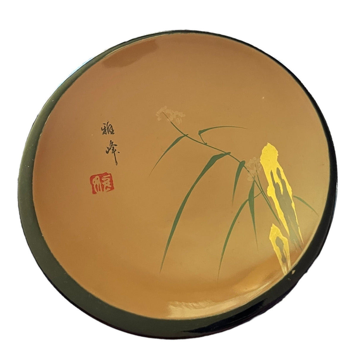 A round wood plate with a glossy warm brown-gold glaze, decorated with green bamboo leaves, a yellow lotus flower, black calligraphy, and a red seal on a white background.