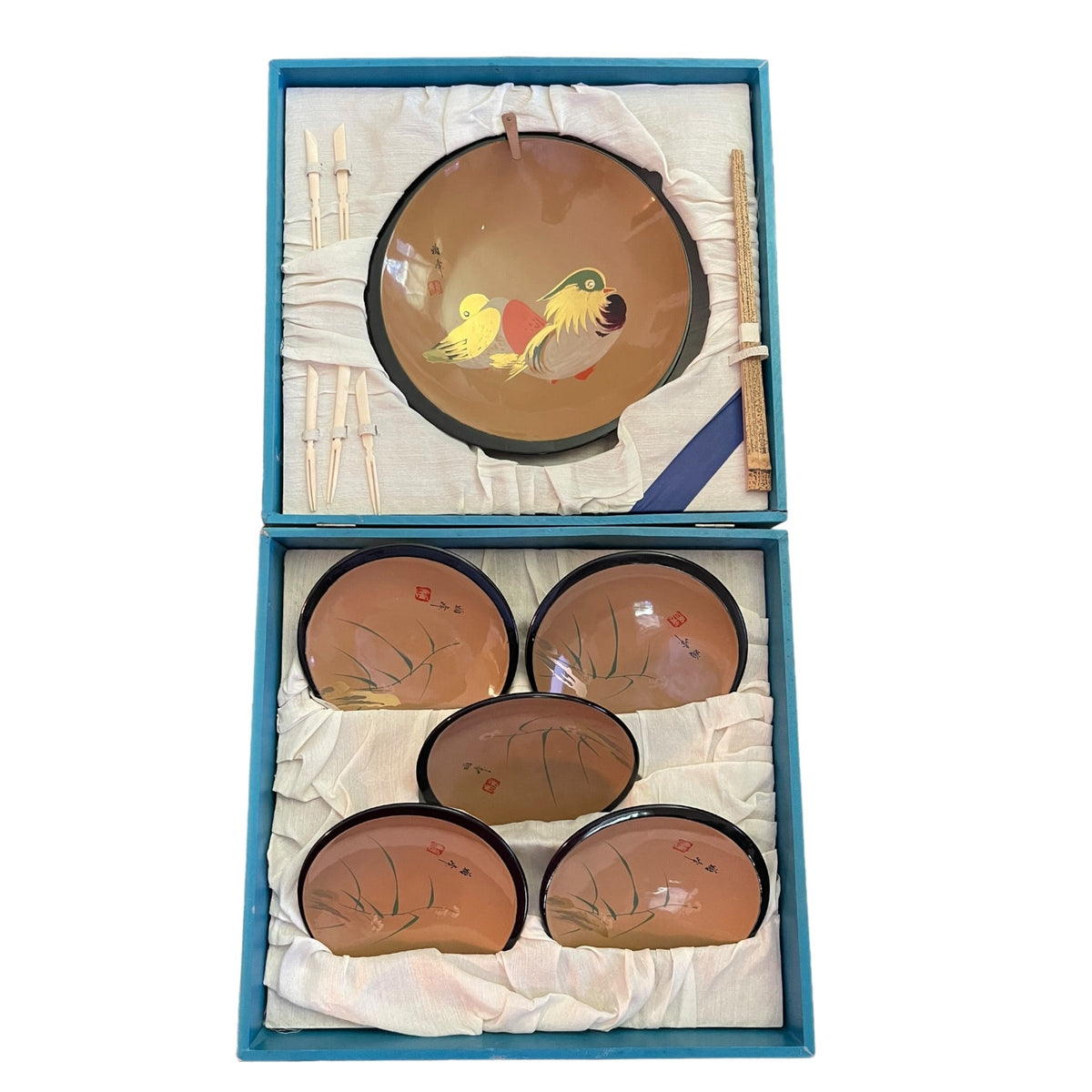 A boxed set of bowls and chopsticks displayed open on a white background. The set includes one large bowl with a colorful bird illustration and four smaller matching bowls, along with chopsticks, all arranged in a blue presentation box with white fabric lining.