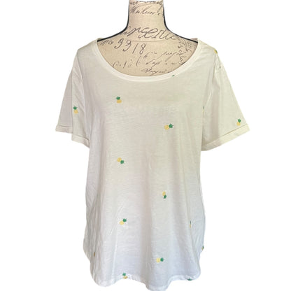 A short-sleeve t-shirt in a white , featuring small embroidered yellow and green pineapple motifs scattered across the front. The shirt is displayed on a vintage-style dress form mannequin against a plain white background.