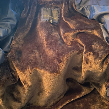 Interior of jacket with Brown textured fabric with a brand label on a blue and white background