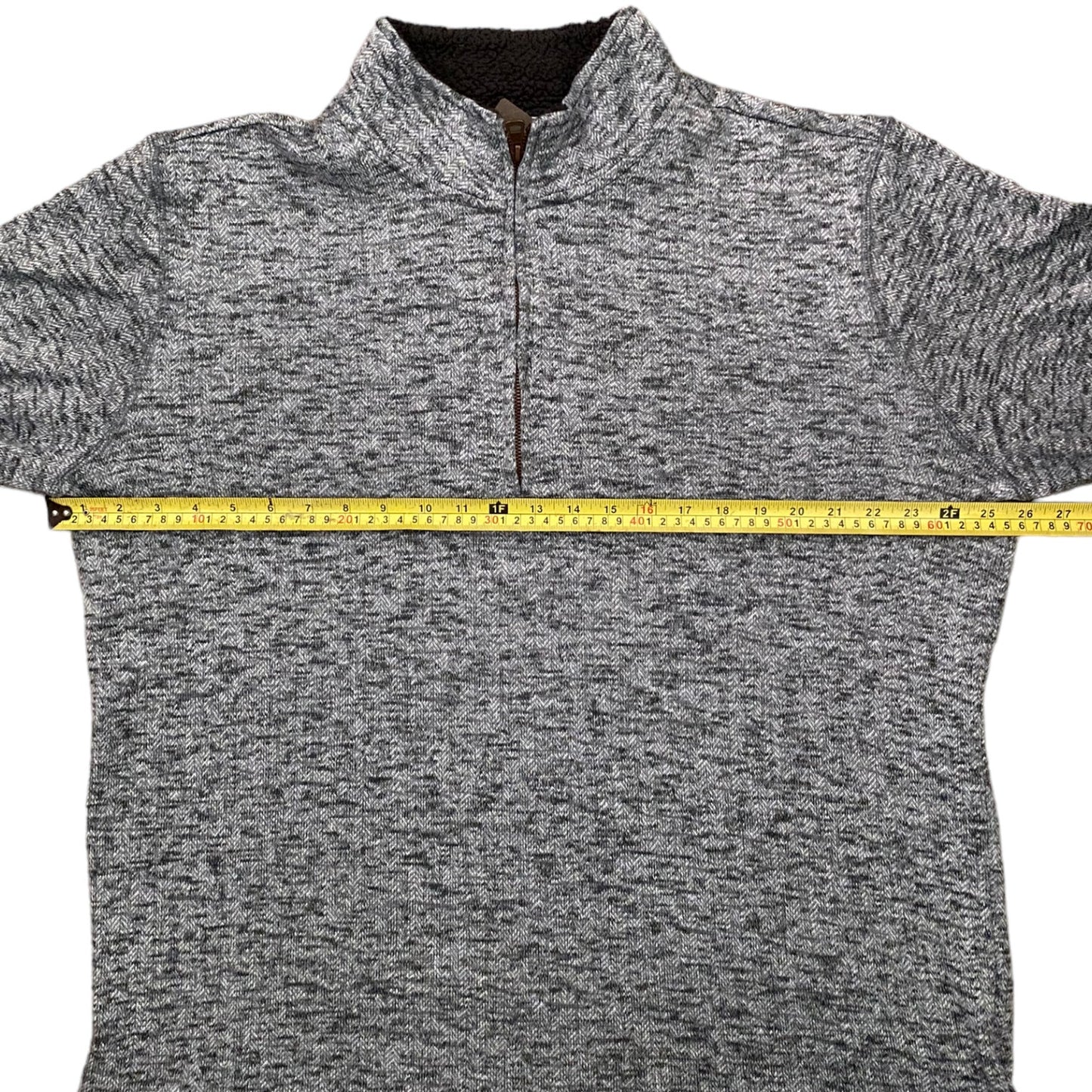 Gray sweater with a measuring tape for size reference on a white background