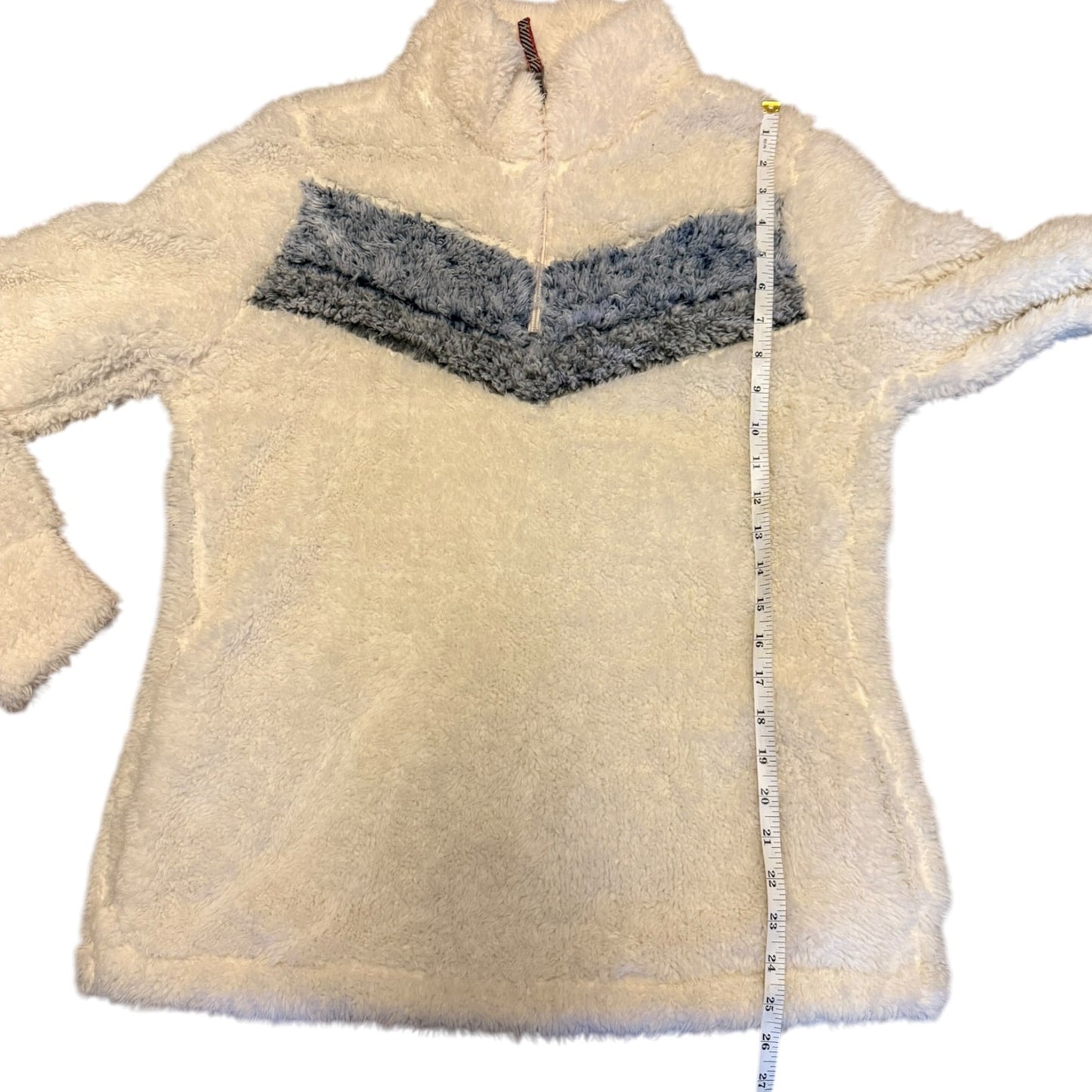 white fleece pullover with gray chevron pattern and a measuring tape draped over it on a white background