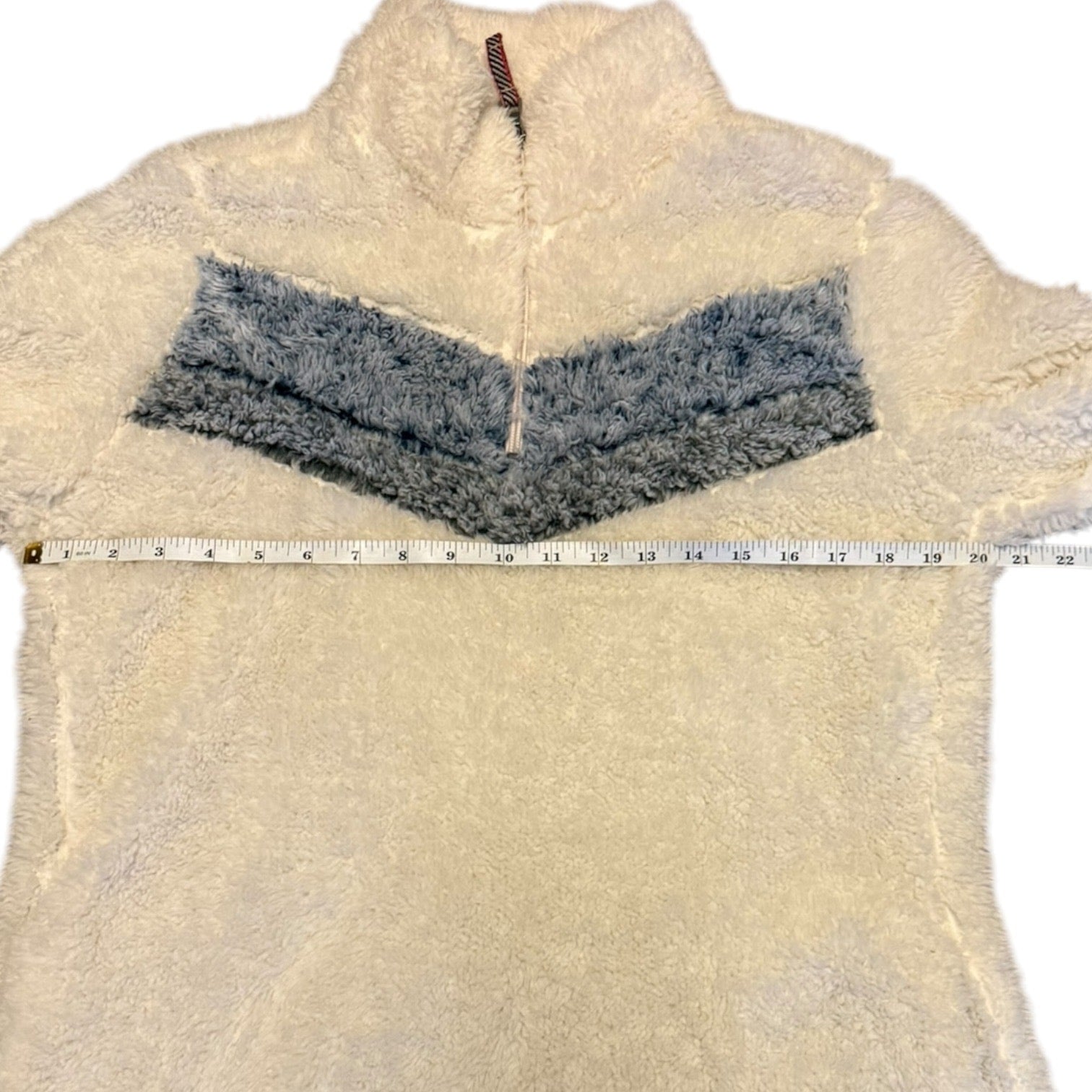 White fleece jacket with gray accents and a measuring tape for size reference on a white background