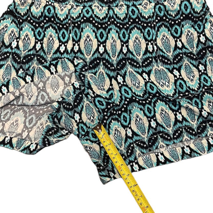 A close-up of patterned shorts  shown with a yellow measuring tape to indicate inseam against a white background.