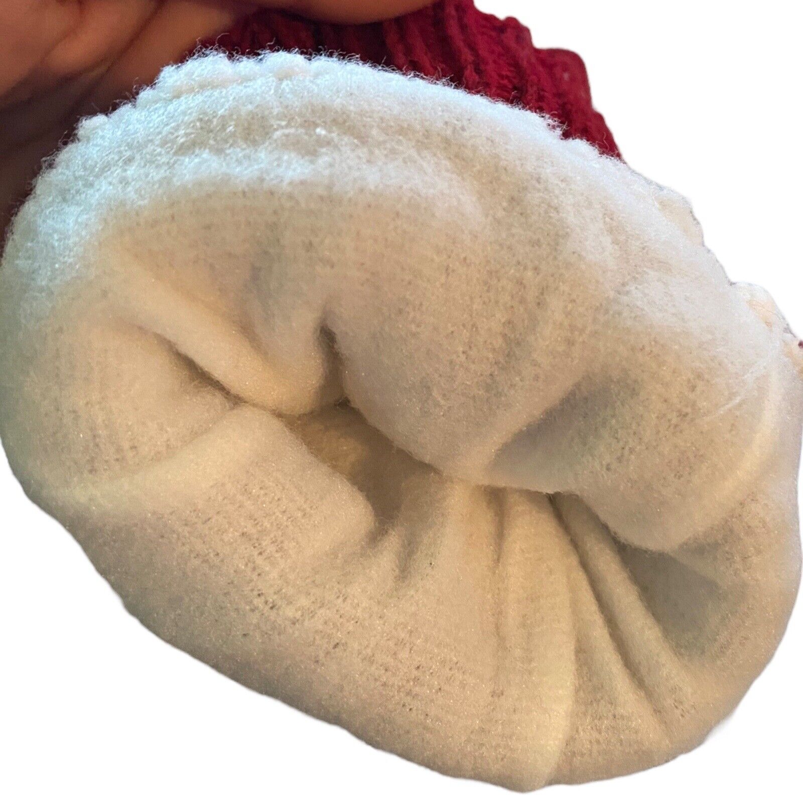 Interior of red gloves, plush white fabric with a red textured knit edge visible at the top, held against a plain white background.