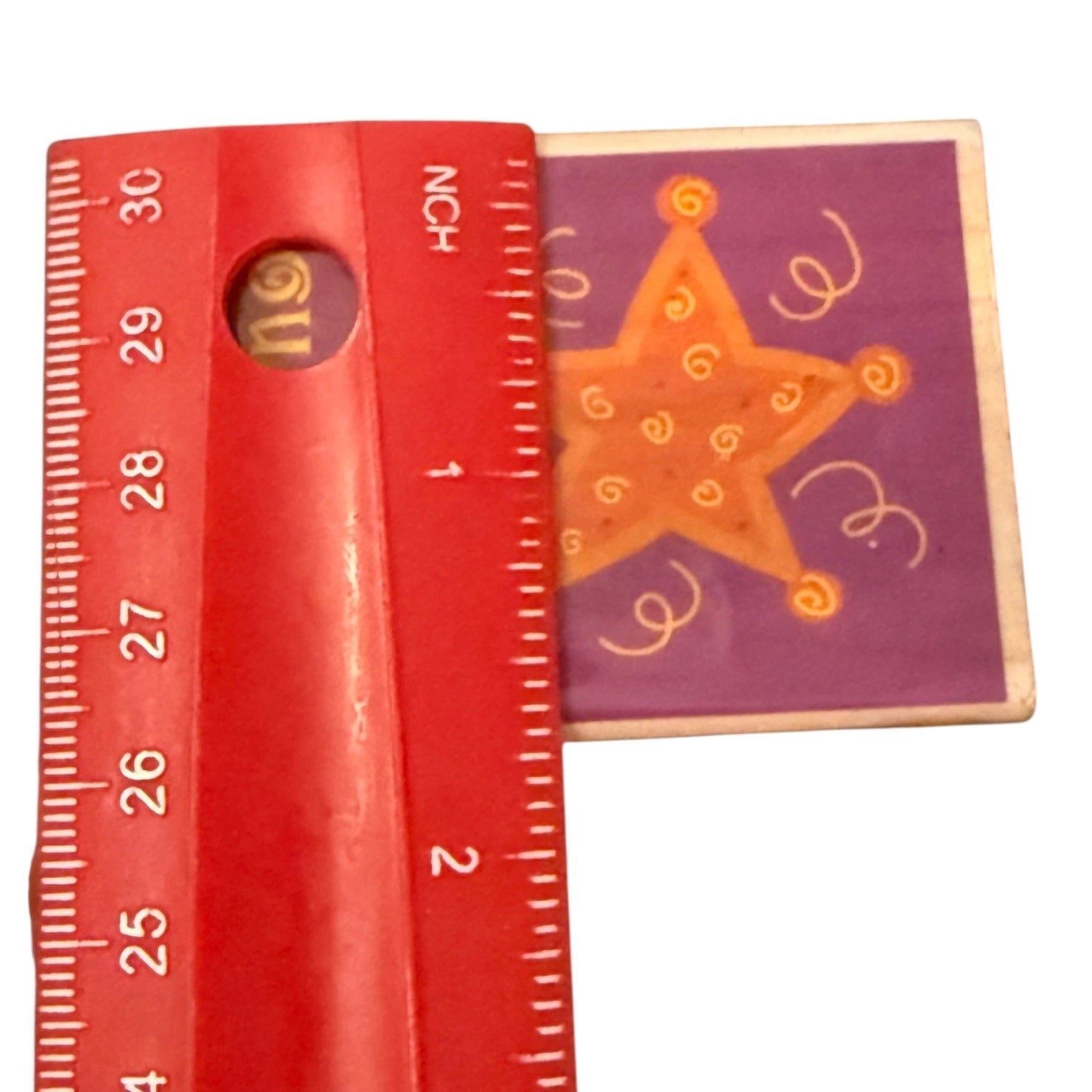 Red ruler 1.75" W next to a star-shaped wooden stamp on a white background