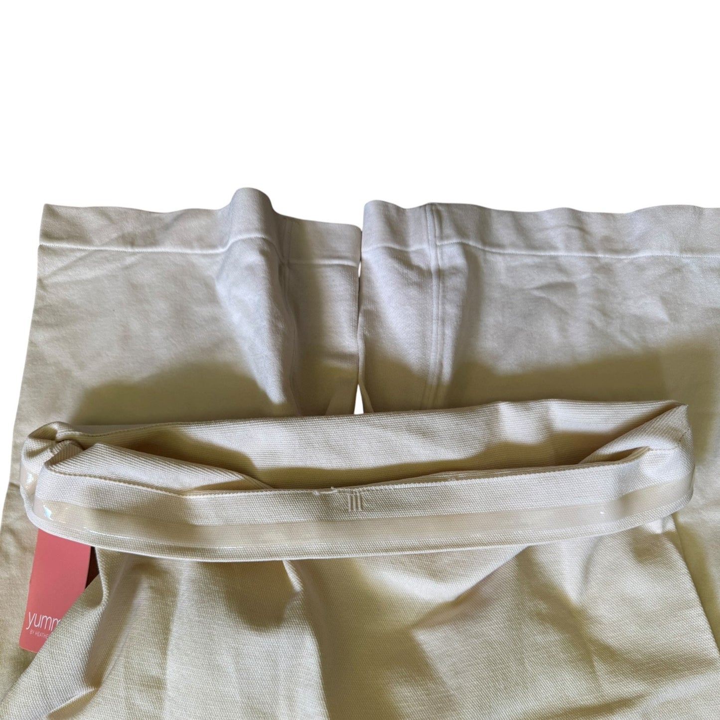 Beige shapewear shorts lining with a pink tag on a white background