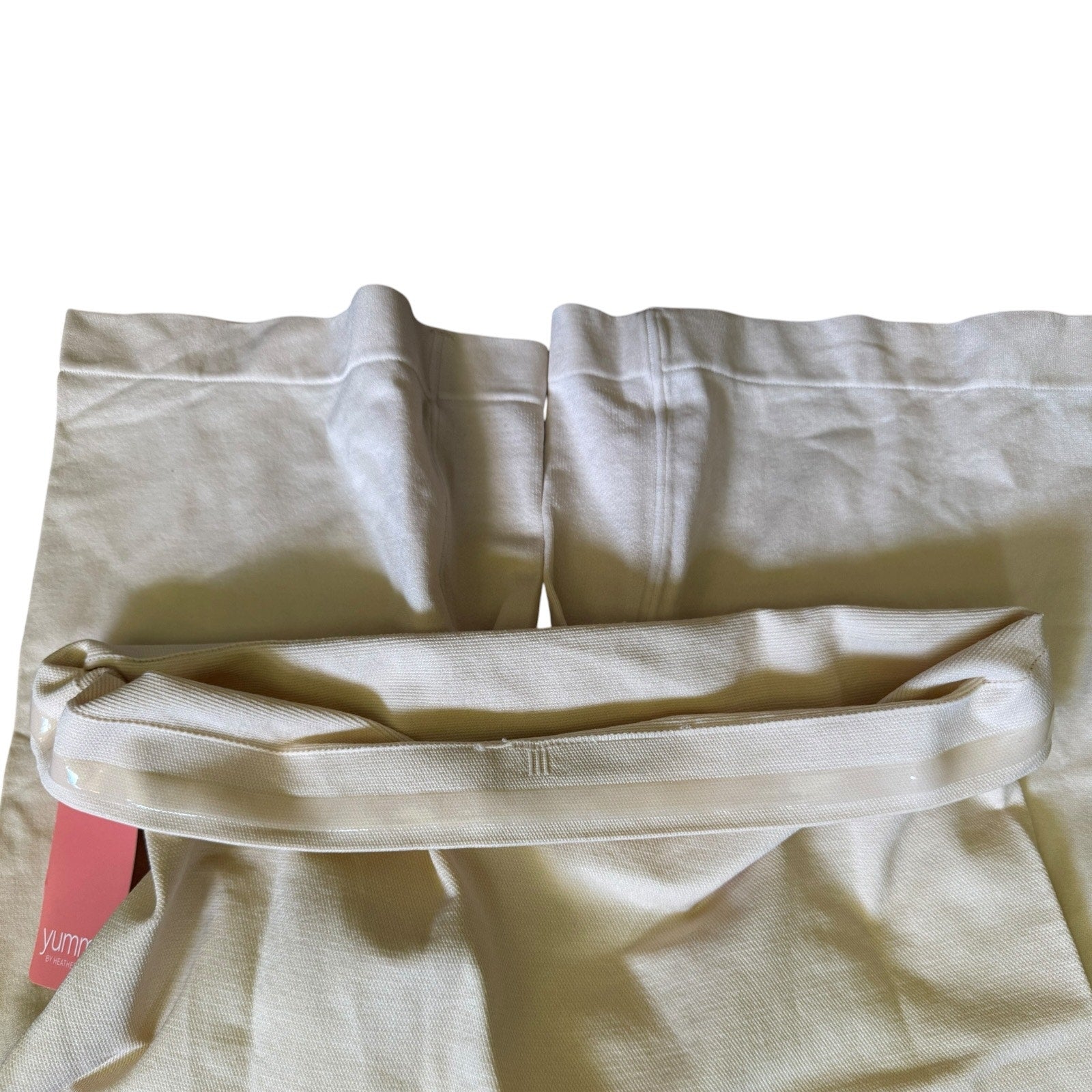 Beige shapewear shorts lining with a pink tag on a white background