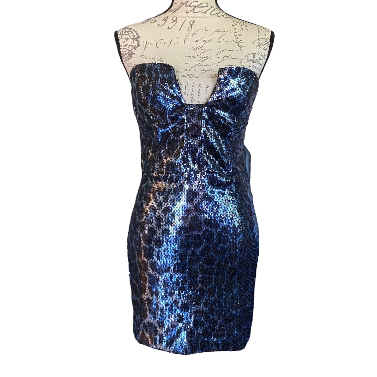 A strapless sequined mini dress with an allover leopard-like pattern, displayed on a cream dress form against a white background.