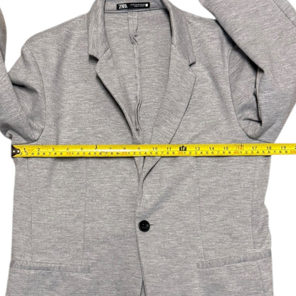 Gray blazer with a measuring tape draped over it on a white background